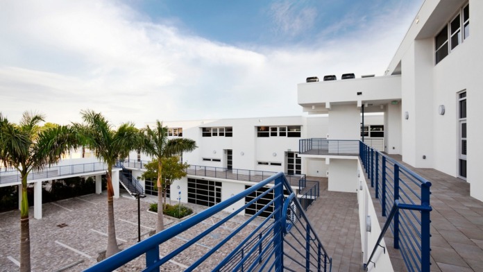 Exterior elevated deck area with blue metal railings overlooking paved courtyard and facility building.