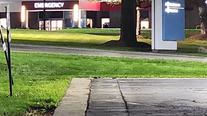 Exterior nighttime view of facility emergency entrance with illuminated signage and landscaped grounds
