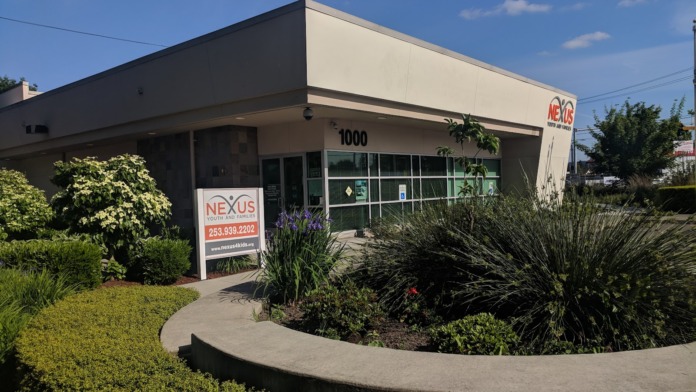 Facility front entry showing curved planter, landscaping, storefront windows, and exterior signage