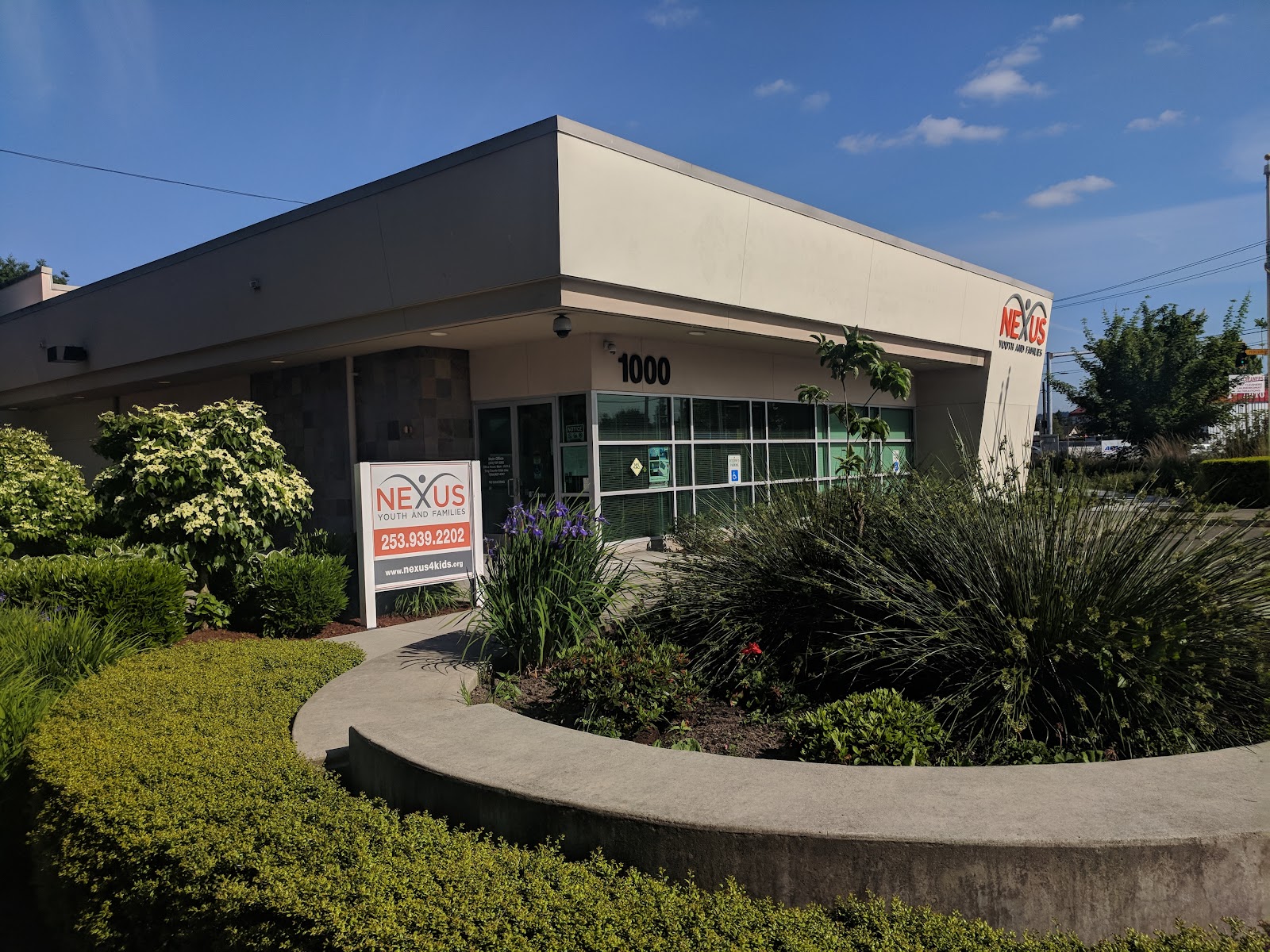 Facility front entry showing curved planter, landscaping, storefront windows, and exterior signage