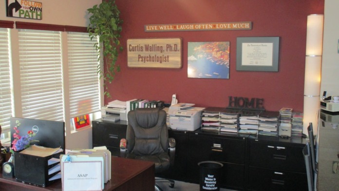 Interior professional office with burgundy walls, desk, filing cabinets, and motivational signage