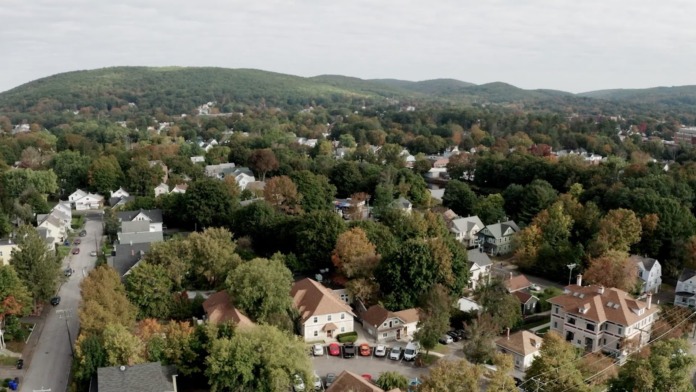 Aerial view of facility grounds within residential neighborhood showing tree coverage, parking areas, and surrounding community