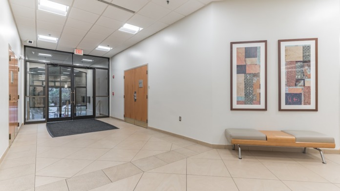 Interior hallway showing multiple office doorways, framed landscape artwork on walls, and fluorescent lighting