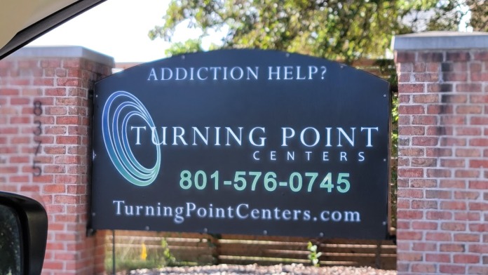 Exterior close-up of Turning Point Centers entrance sign mounted on brick pillars with contact information and website
