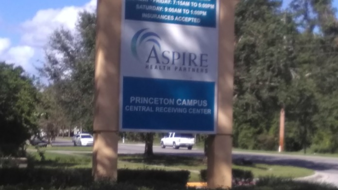 Exterior sign displaying Aspire Health Partners name with address 1800 Mercy Drive and pharmacy information with hours