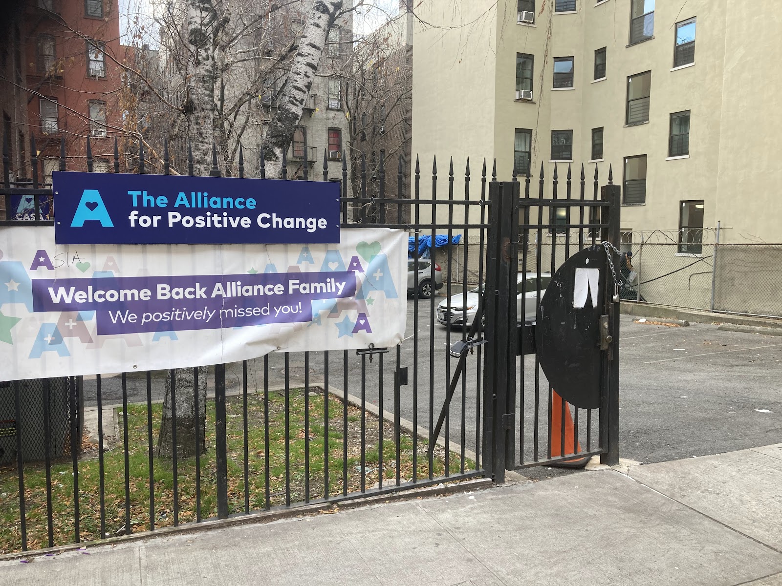 Exterior fence with welcoming banner for The Alliance for Positive Change facility entrance.