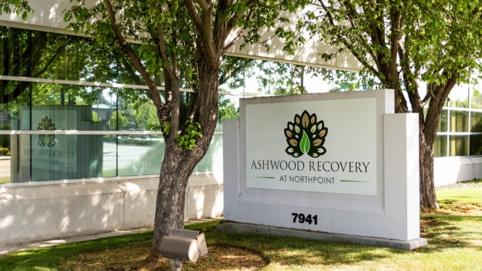 Exterior signage for Ashwood Recovery at Northpoint with landscaped grounds, mature trees, and glass building visible in background