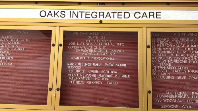 Interior entryway bulletin board mounted on brick wall with facility name and service directory information