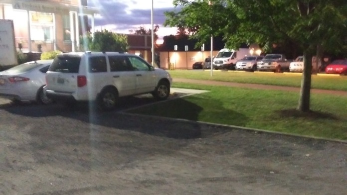 Exterior view of facility showing parked vehicles, brick building facade, landscaping, and American flag at dusk