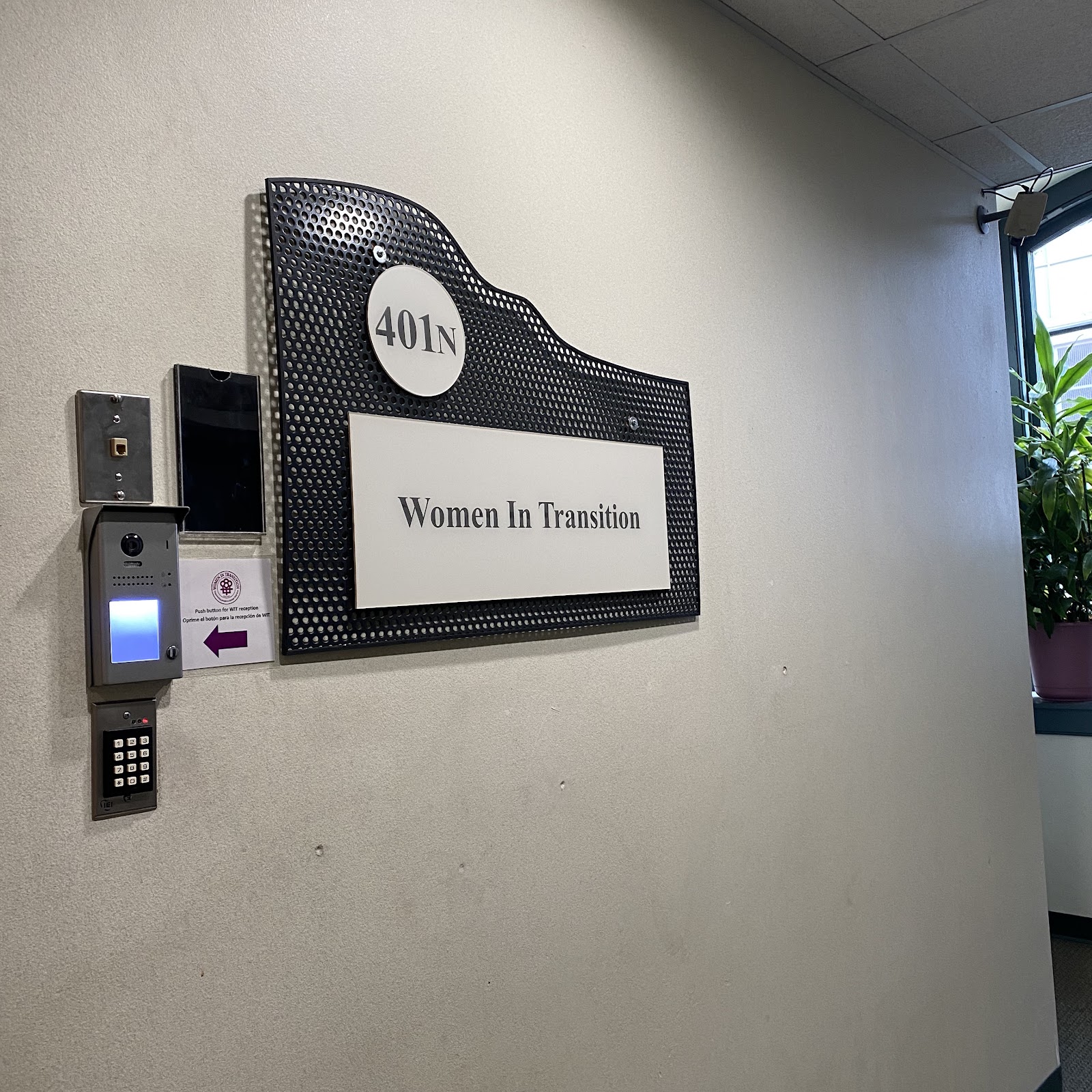 Interior hallway showing Women In Transition office signage on wall with suite number 401N and access control system