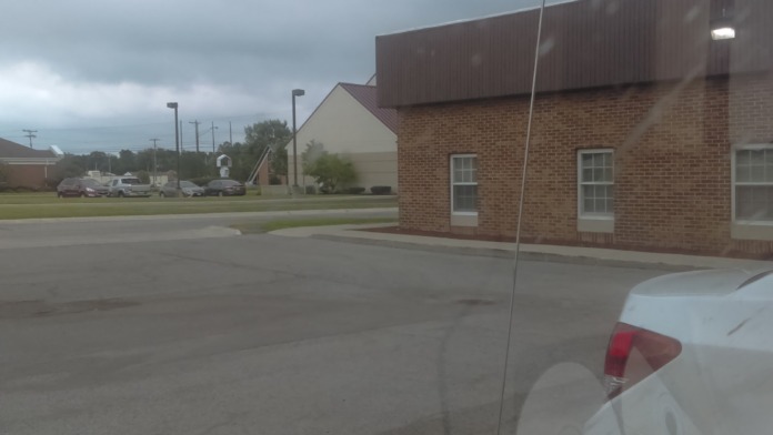Exterior view of brick treatment facility building with parking lot and vehicles