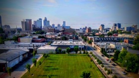 Exterior aerial view of treatment facility with manicured green lawn, landscaping, adjacent buildings, and downtown Louisville skyline in background