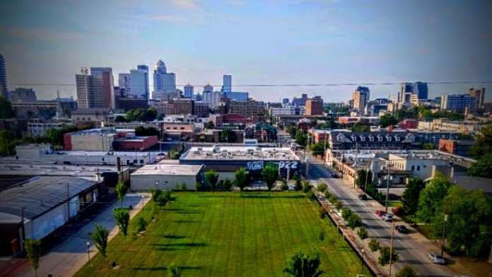 Exterior aerial view of treatment facility with manicured green lawn, landscaping, adjacent buildings, and downtown Louisville skyline in background