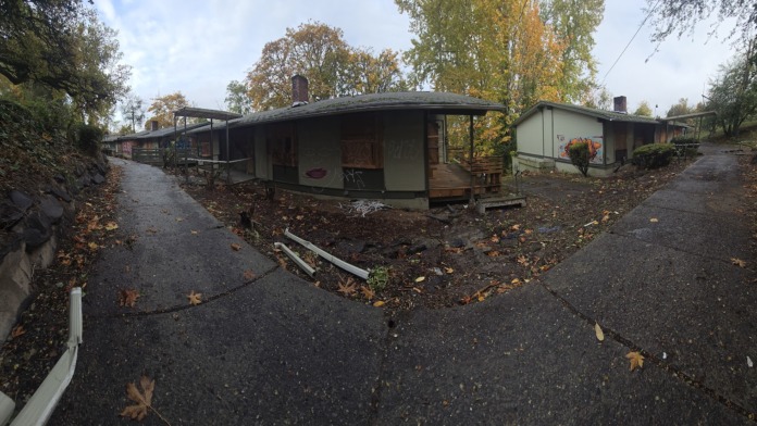 Exterior view of treatment facility grounds showing multiple residential buildings with covered structures, paved pathways, and autumn foliage
