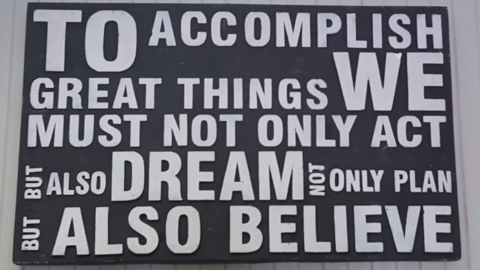 Interior wall signage with motivational quote about accomplishing great things, acting, dreaming and believing