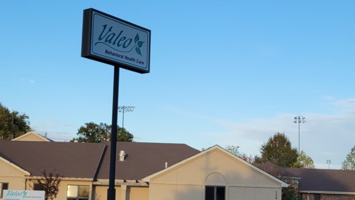 Valeo Behavioral Health Care pole sign with facility building structures and landscaping visible in background