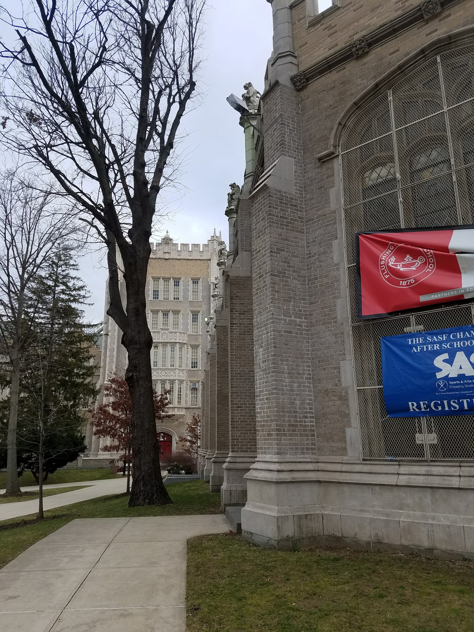 Exterior side view of stone building with decorative architectural details, concrete pathway, and adjacent structures