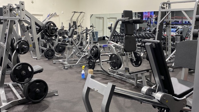 Interior fitness center with multiple exercise machines, weights, and cardio equipment arranged throughout spacious room