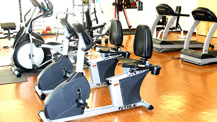 Interior fitness center with stationary bikes, treadmills, and exercise equipment on hardwood flooring