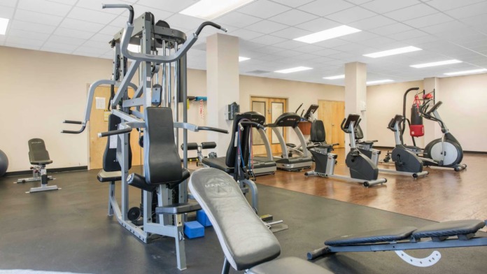 Interior fitness facility with multi-station strength training equipment, exercise machines, treadmills, and bicycles on flooring