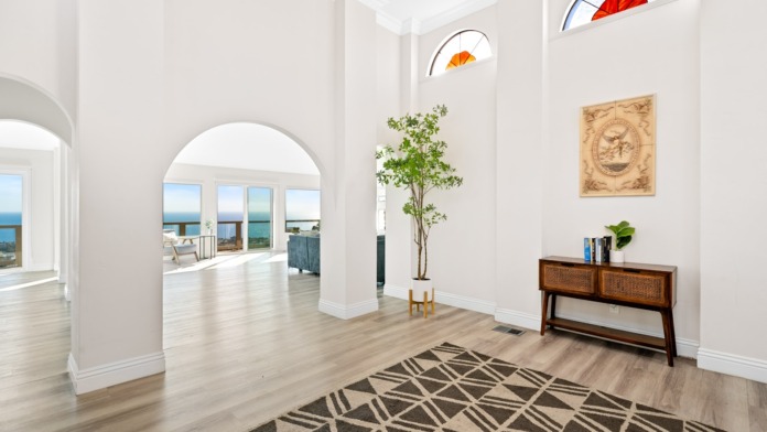 Interior foyer with arched architectural elements, wooden console furniture, plants, and ocean views
