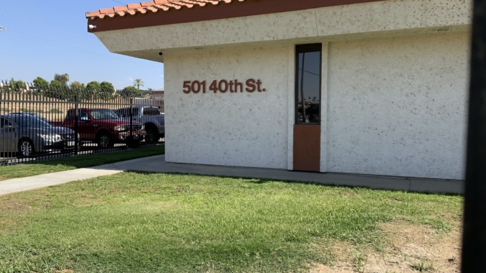 Exterior front facade showing street address, stucco walls, roof overhang, and entry door with fencing
