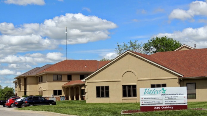Front exterior of Valeo treatment facility complex showing main building with signage identifying multiple service departments