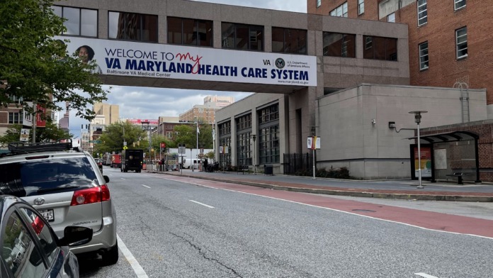 Interior entryway showing Welcome to VA Maryland Health Care System banner, parked vehicles visible through large windows