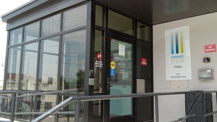 Close-up exterior view of Eskenazi Health Center Pedigo entrance showing address 1112 Southeastern Ave and facility accessibility signage