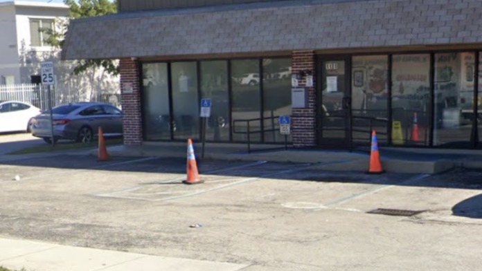 Exterior front entrance showing brick treatment facility with tan upper section, ramp access, entrance doors, traffic cones, and parking area.