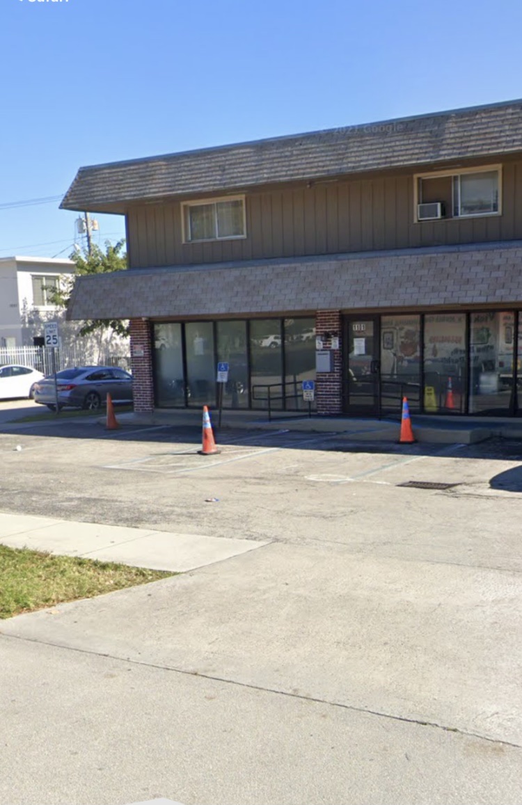 Exterior front entrance showing brick treatment facility with tan upper section, ramp access, entrance doors, traffic cones, and parking area.