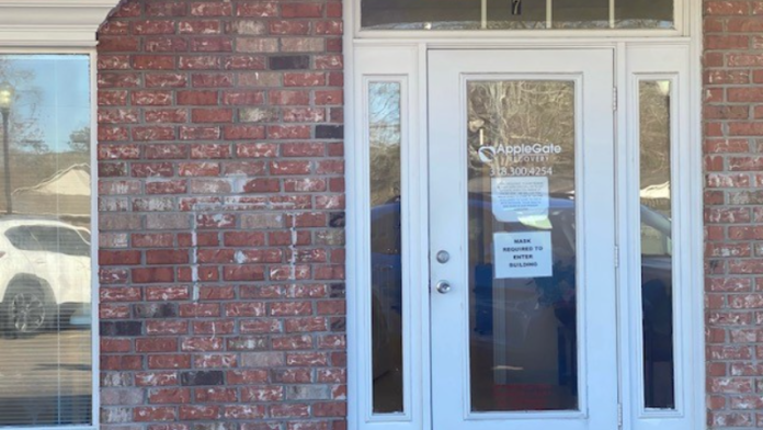 Exterior front entrance of treatment facility showing white entry doors with AppleGate Recovery signage and brick architecture