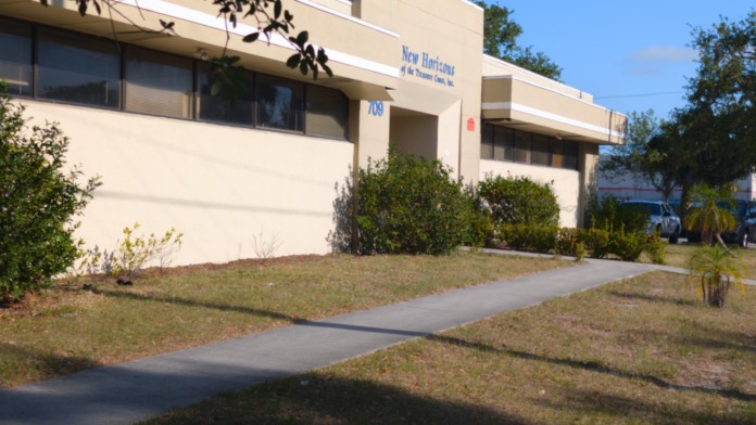 Exterior front entrance showing New Horizons facility name, address 709, dark glass doors, and landscaping