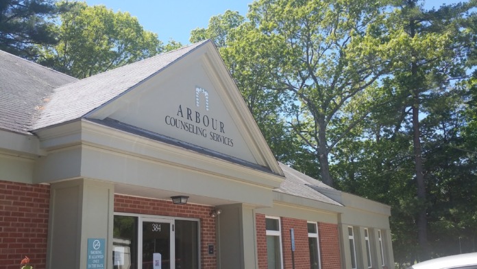 Exterior front entrance of counseling services building showing brick facade, white trim, entry doors, and landscaped plantings
