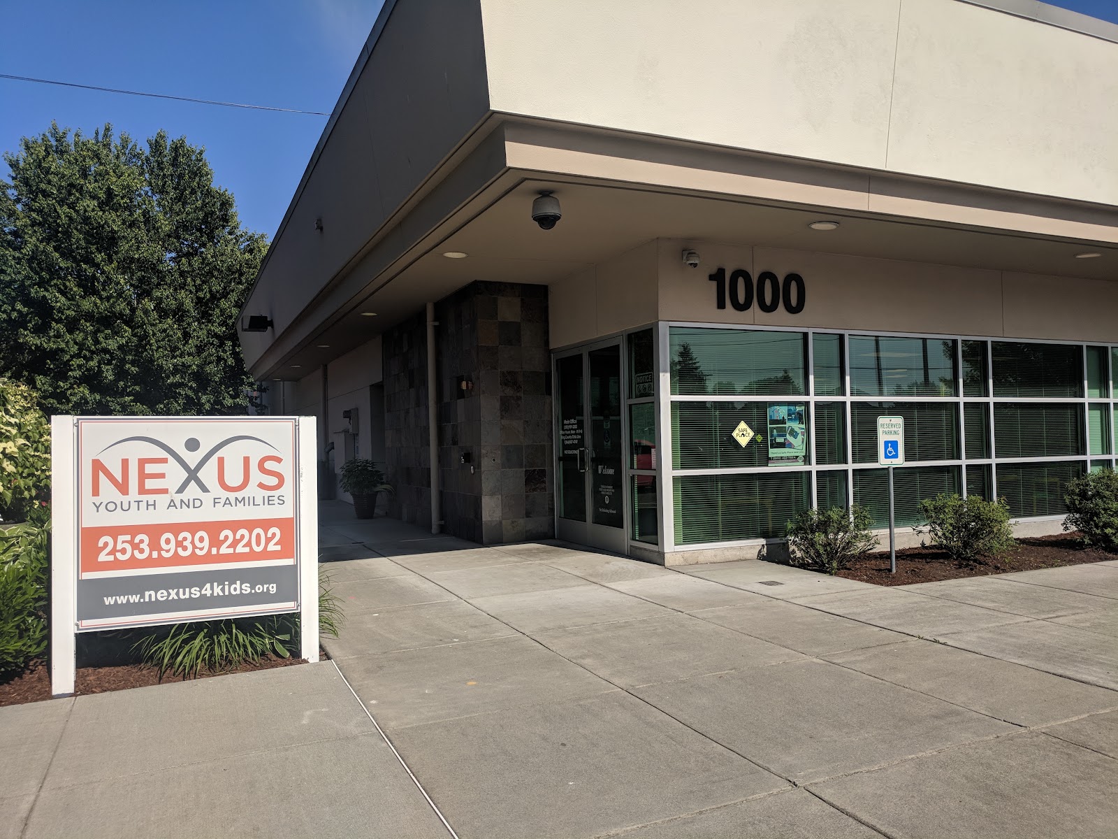 Facility front with white signage board displaying contact information, phone number, and address 1000