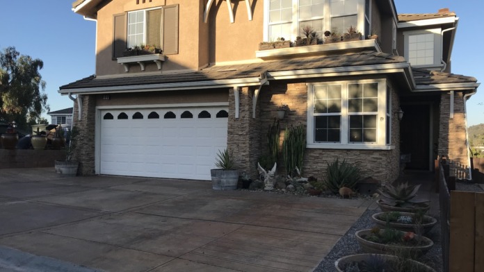 Exterior view of two-story residential home with garage, landscaped front yard, and concrete driveway