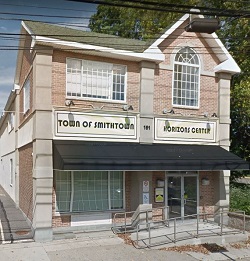 Exterior of two-story brick facility building with storefront entrance, large windows, and peaked roof design.