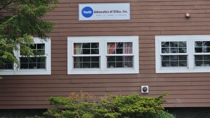 Exterior view of two-story youth treatment center building with brown siding, white trim windows, and facility identification sign.