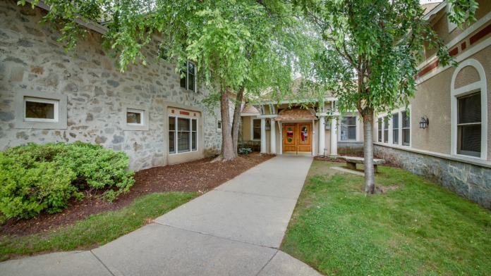 Exterior front facade showing cream and stone construction with columned portico entry and manicured landscaping