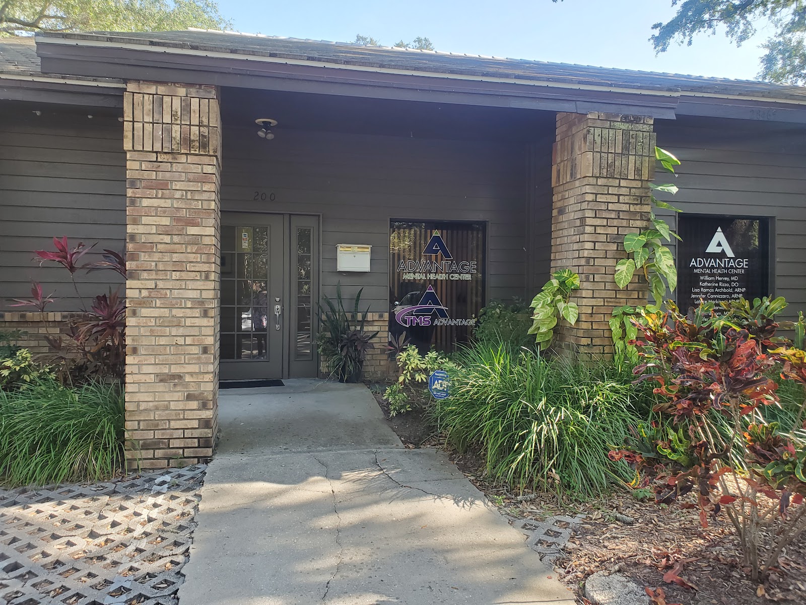 Front exterior of single-story brick facility with entrance, professional signage, and manicured landscaping