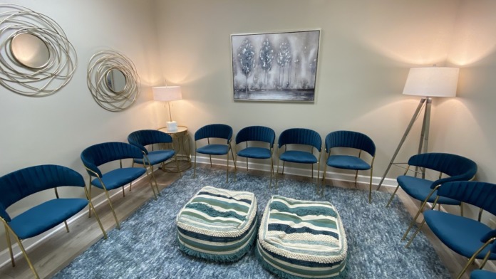 Interior counseling space with blue padded chairs in semi-circle arrangement, neutral walls, landscape artwork, and table lamps