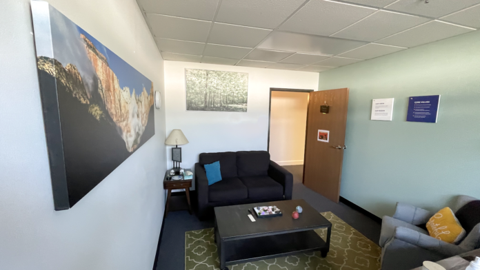 Interior common area with multiple black sofas, coffee table, wall artwork, landscape paintings, and seating arrangements for group activities