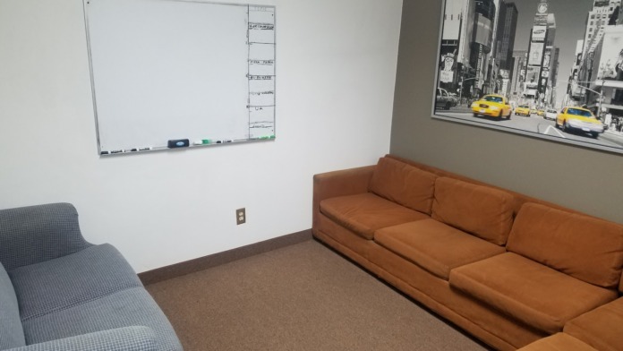 Interior meeting space with upholstered seating, whiteboard, and motivational wall messaging