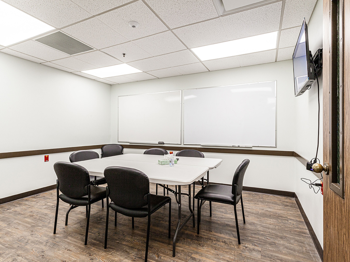 Interior meeting room with white boards, conference table, black chairs, and professional presentation setup