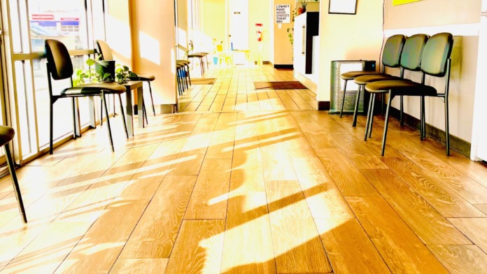 Interior therapy room with wooden flooring, chairs for group seating, television, motivational wall displays, and bright natural lighting from windows