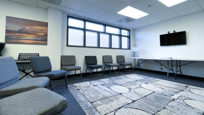 Interior therapy room with comfortable seating, natural lighting, artwork on walls, and entertainment equipment including keyboard and television
