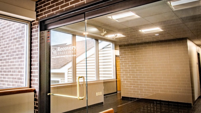 Interior entrance corridor with glass door, brick walls, wooden frame, cream colored walls, and flooring