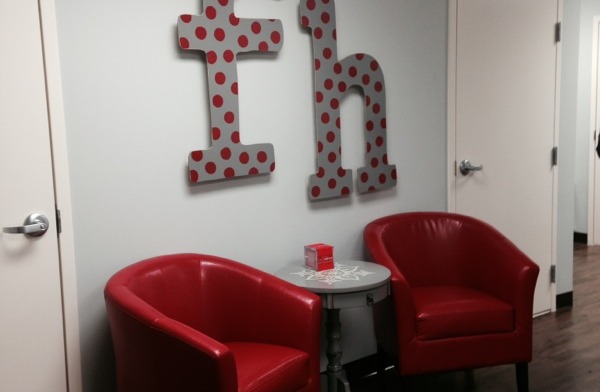 Interior hallway with red seating nook, polka dot wall lettering reading 'fh', side tables, and white doors