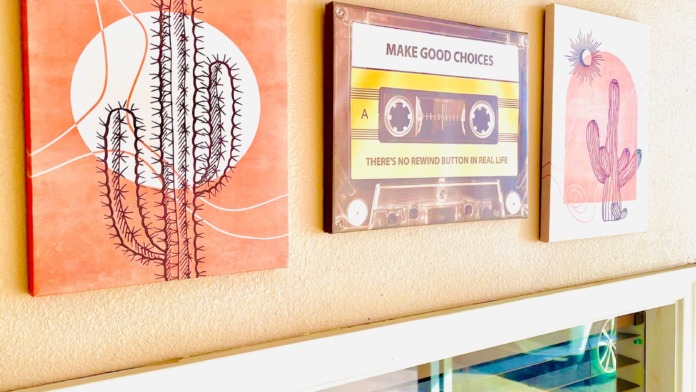 Interior wall featuring motivational artwork including cactus and cassette tape designs with recovery-themed messaging, wooden floors and seating areas
