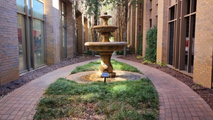 Brick-enclosed courtyard space with central decorative fountain, landscaping, and surrounding multi-story medical buildings